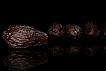 Group of four whole dried brown date fruit isolated on black glass