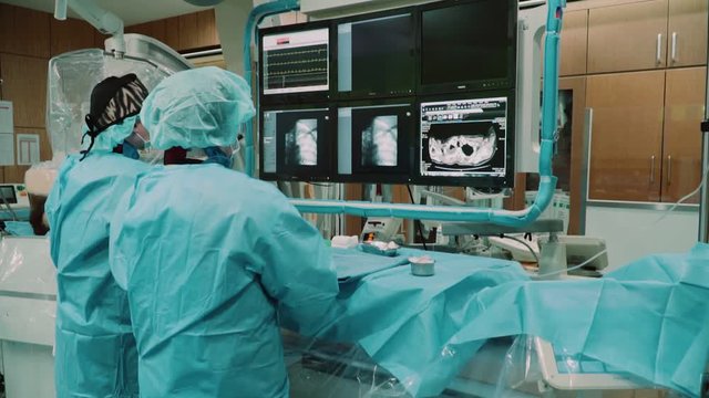 Operating room in which doctors perform surgery looking into monitors
