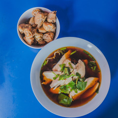 Chicken noodles soup in bowl at noodle shop street .	