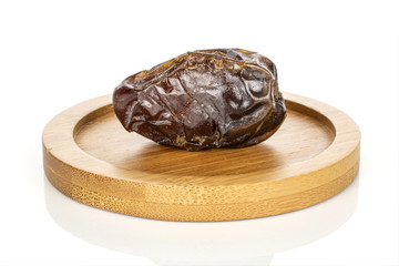 One whole dried brown date fruit on round bamboo coaster isolated on white background