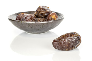 Lot of whole dried brown date fruit in glazed bowl isolated on white background