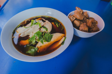 Chicken noodles soup in bowl at noodle shop street .	