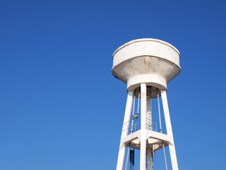 White concrete water tank on the tower: large outdoor public water storage tanks for water supply in villages or communities in the city On the sky background with copy space.