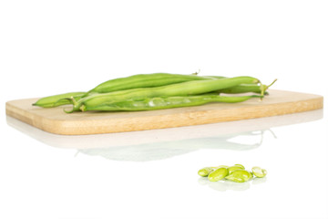 Lot of whole lot of pieces of snap green bean on bamboo cutting board isolated on white background