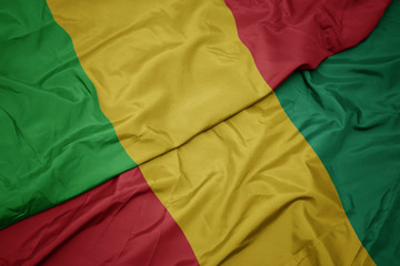 waving colorful flag of guinea and national flag of mali.