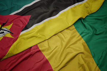 waving colorful flag of guinea and national flag of mozambique.