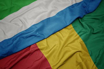 waving colorful flag of guinea and national flag of sierra leone.