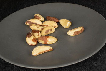 Lot of whole brazil brown nut on gray ceramic plate on grey stone