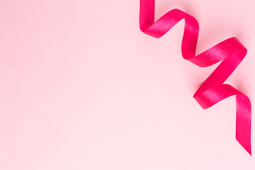 Gift ribbon fuchsia color on pink background. Minimalistic composition for the holidays.