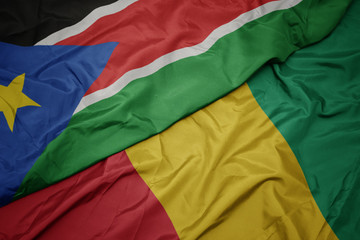 waving colorful flag of guinea and national flag of south sudan.