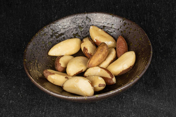 Lot of whole brazil brown nut in glazed bowl on grey stone