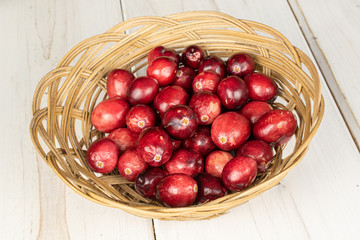 Lot of whole fresh red cranberry in round rattan bowl on white wood