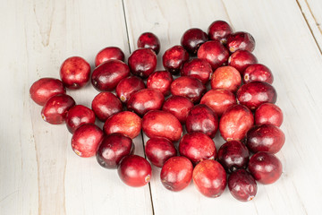 Lot of whole fresh red cranberry on white wood