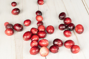 Lot of whole fresh red cranberry on white wood