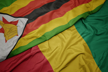 waving colorful flag of guinea and national flag of zimbabwe.