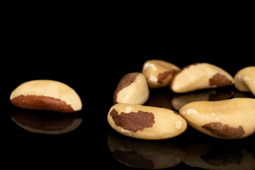 Fototapeta na wymiar Group of seven whole brazil brown nut isolated on black glass
