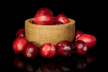 Lot of whole fresh red cranberry in bamboo bowl isolated on black glass