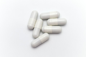 Prescription drugs, capsules of white colors. On white background.