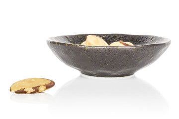 Lot of whole unshelled brazil brown nut in glazed bowl isolated on white background