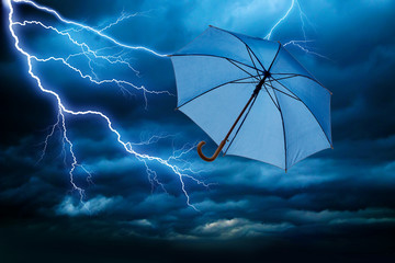 blauer Regenschirm fiegt bei Sturm mit Gewitter davon