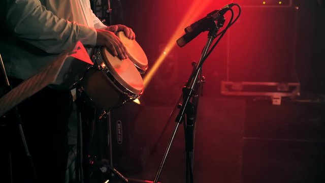 Bongo drum percussionist in white classic shirt and bass player perform on stage