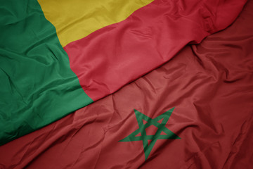 waving colorful flag of morocco and national flag of benin.