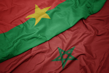 waving colorful flag of morocco and national flag of burkina faso.