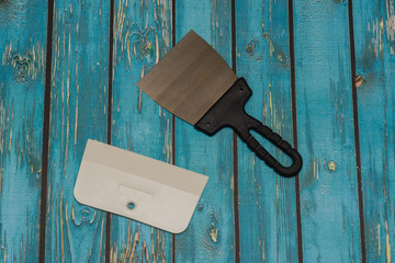metal and rubber spatulas for repair work on a blue wooden background