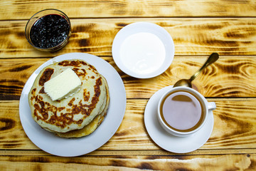 pancakes with butter and sour cream, Maslenitsa a large stack of fried pancakes with tea, selective focus, top view