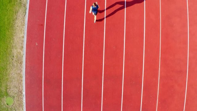 Top view of a track runner athlete running on stadium lane, 4k