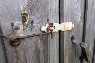 Rusty hook locks the wooden gate of an old barn