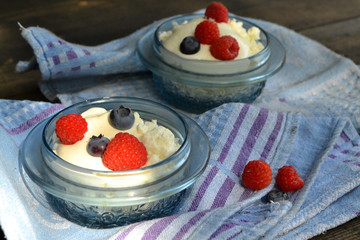 Yogurt and fresh raspberry and blueberry parfait with cream and granola.