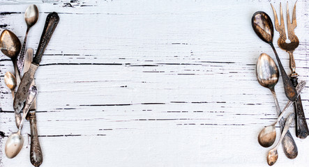 Vintage cutlery - spoons, forks and knives on an old wooden background.