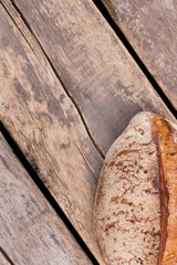 Loaf of homemade bread on rustic wooden background. Healthy wheat bread on cracked wooden boards. Space for text.