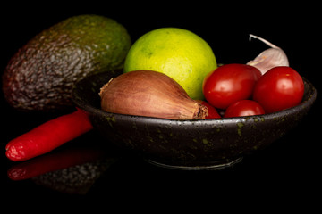 Lot of whole ingredient guacamole in glazed bowl isolated on black glass
