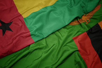 waving colorful flag of zambia and national flag of guinea bissau.