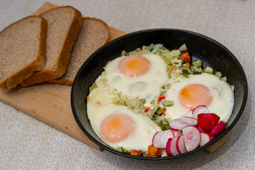 Three eggs with vegatables on frying pan