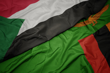 waving colorful flag of zambia and national flag of sudan.
