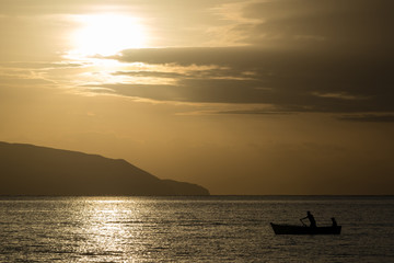 Fototapeta na wymiar Sunrise seascape with mountains and fisherman boat