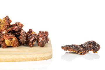 Lot of whole dried red tomato piece one separated on bamboo cutting board isolated on white background