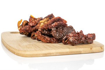 Lot of whole dried red tomato piece on bamboo cutting board isolated on white background