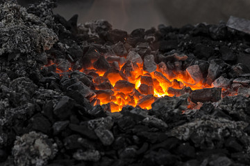 Embers glow in a bonfire. Fire, heat, coal and ash with with flying sparks.