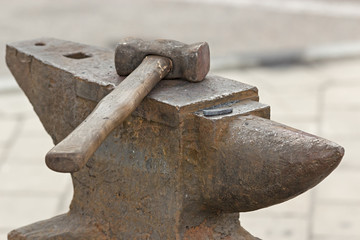 Old rusty hammer lies on the anvil. Blacksmith, metalsmith, farrier tools. Close view.