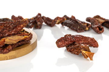 Lot of whole arranged dried red tomato piece on round bamboo coaster isolated on white background