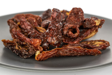 Lot of whole dried red tomato piece on gray ceramic plate isolated on white background