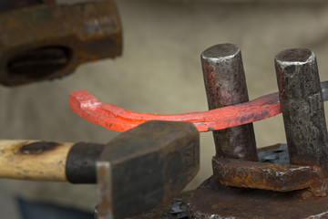 The blacksmith makes a hot red  iron horseshoe with a hammer.