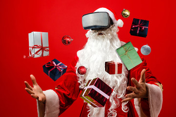 Santa Claus wearing virtual reality goggles, on a red background. Christmas