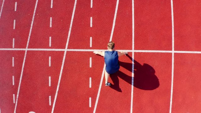 Top view of a track runner athlete at starting line on stadium lane, 4k