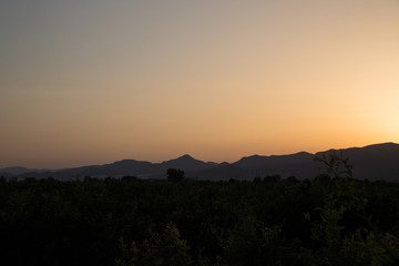 Beautiful landscape. Sunset. The sun sets over the mountains. Yellow sky and dark mountains.