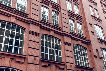 Fototapeta na wymiar The facade of a classic red brick building with large windows. Brick architecture of a prestigious area. Expensive real estate.